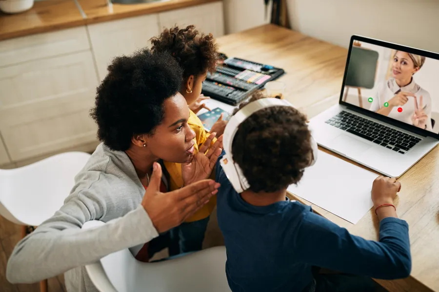 A parent and two children on a video call with their African language tutor